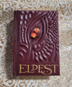 A ridged red leather dragon book with a piercing orange eye. Eldest is in gold letters at the bottom of the book's cover.